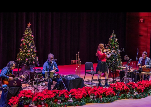 Musicians on stage with poinsettias and a Christmas Tree