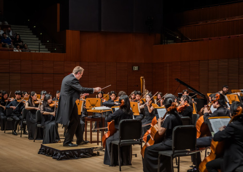 Man in suit on podium conducting an Orchestra