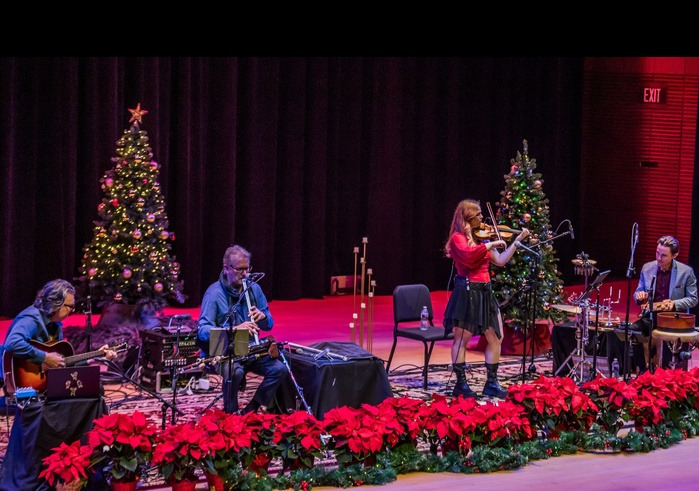 Musicians on stage with poinsettias and a Christmas Tree