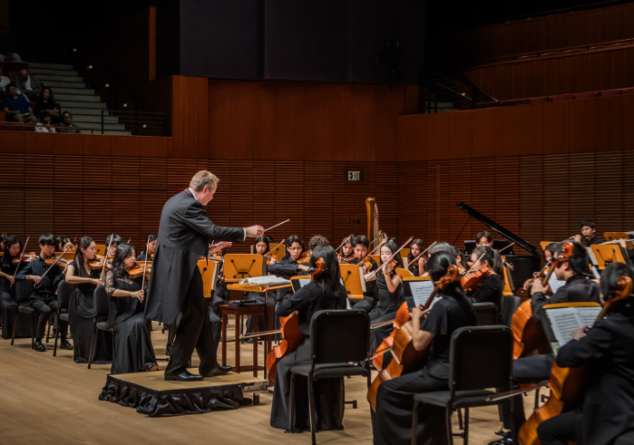 Man in suit on podium conducting an Orchestra